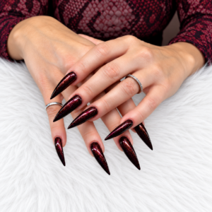 Client wearing Lady LaLa deep burgundy gel polish with copper and fuchsia shimmer on long stiletto nails