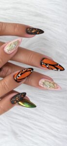 Orange butterfly wing nail art created with Solar Flare topped with Lions Gate cat eye, with black outlines and white dots.