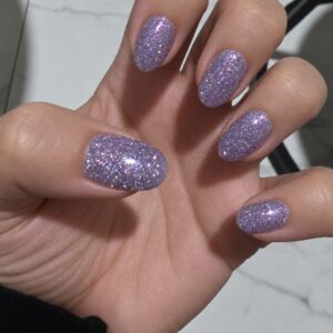 Ava lavender flash-reflective gel polish shown on a client’s short rounded nails with sparkling multidimensional glitter.