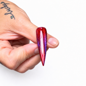 True Believer purple cat eye layered over Cyn Not Sin ruby cat eye on a pointed nail swatch against a white background.