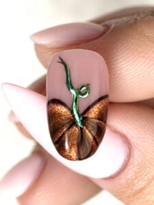 Copper cat-eye pumpkin nail art made with Lionsgate gel polish, black outlines, and a curled green chrome stem on a sheer pink base.