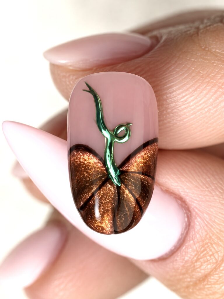 Copper cat-eye pumpkin nail art made with Lionsgate gel polish, black outlines, and a curled green chrome stem on a sheer pink base.